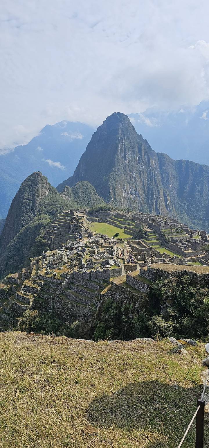 Ruines du Machu Picchu situées dans un paysage montagneux sous un ciel bleu.