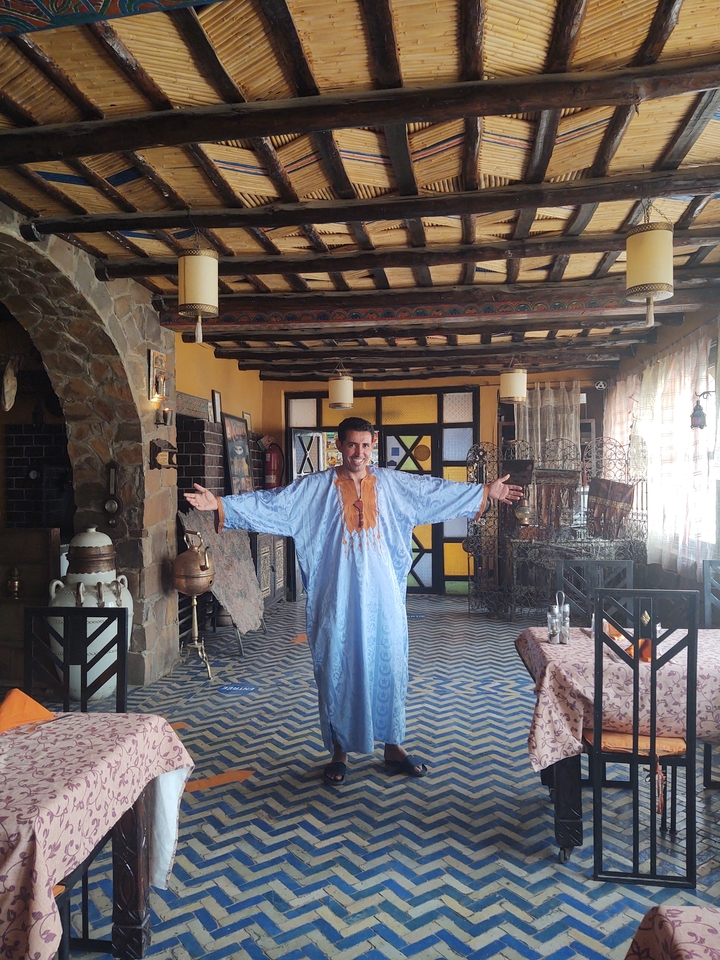 Homme en tenue traditionnelle dans une pièce décorée avec des meubles.