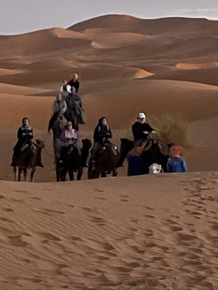 Des gens chevauchant des chameaux à travers les dunes du désert.