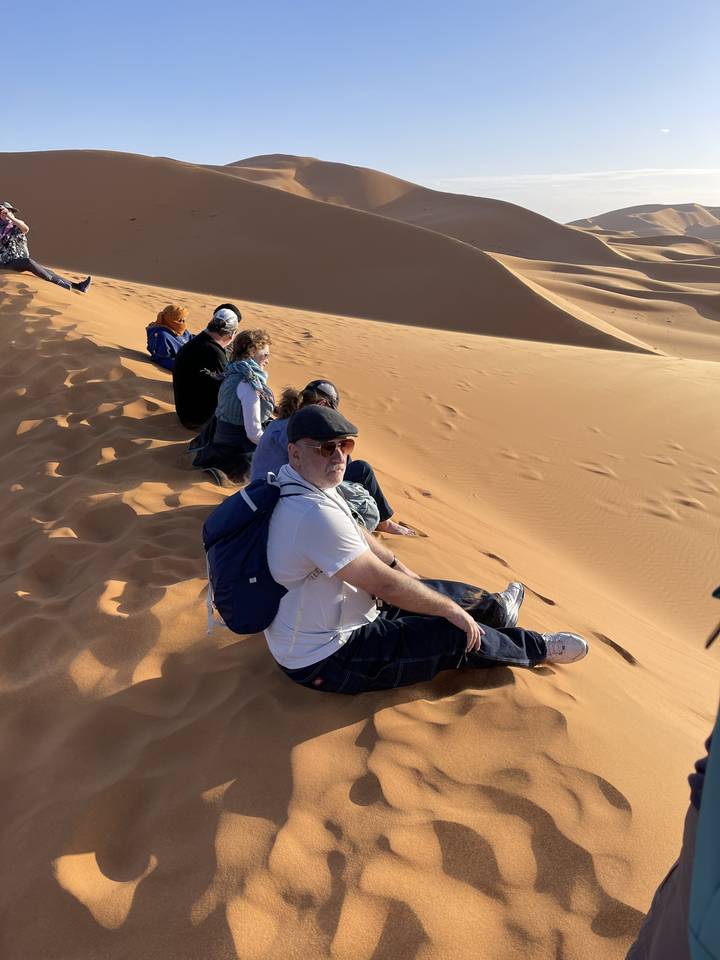 Des gens assis sur une dune de sable dans le désert.