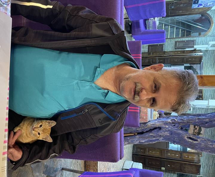 Homme assis à l'intérieur sur une chaise violette.