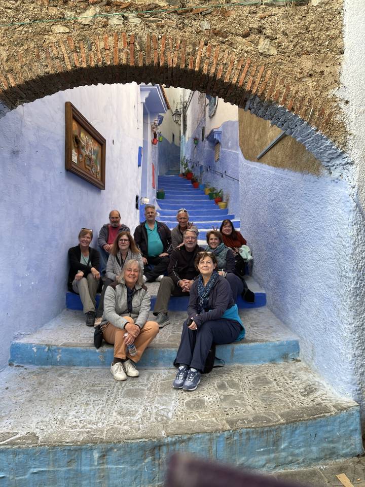 Groupe de personnes assises sur des escaliers dans une ruelle de couleur bleue.