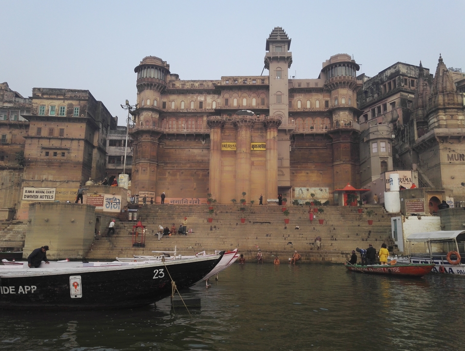 Ghat historique avec des bateaux amarrés sur la berge de la rivière.