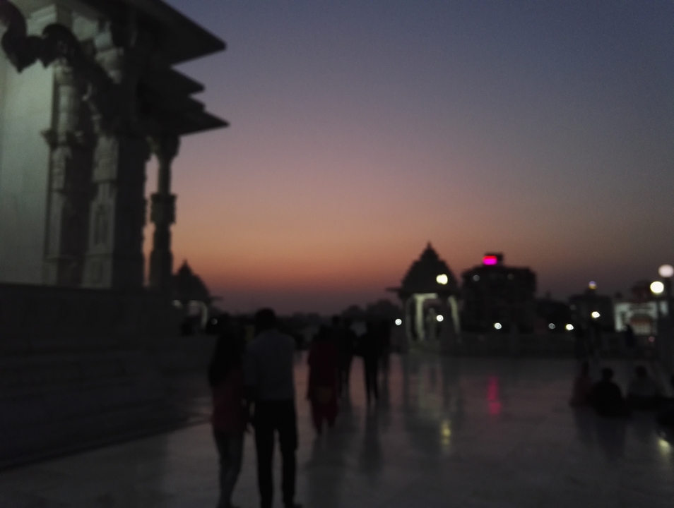 Silhouettes de personnes et de structures contre un coucher de soleil.