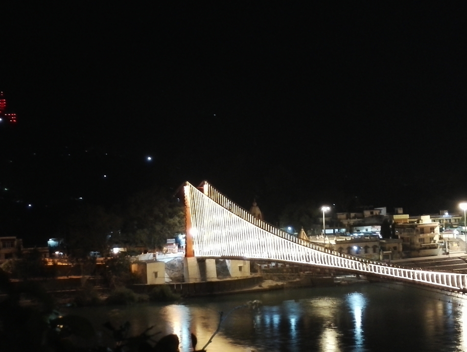 Vue nocturne d'un pont suspendu illuminé.