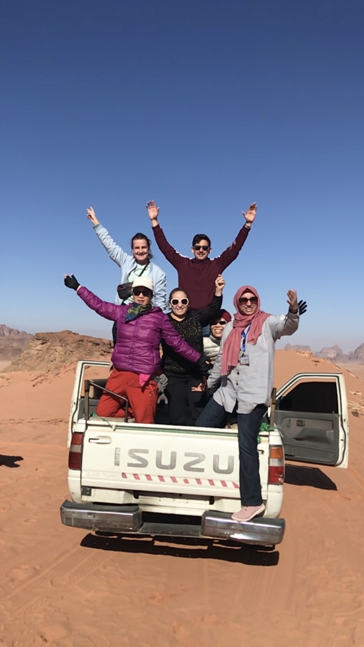 Groupe d'amis prenant la pose au sommet d'un véhicule dans le désert.