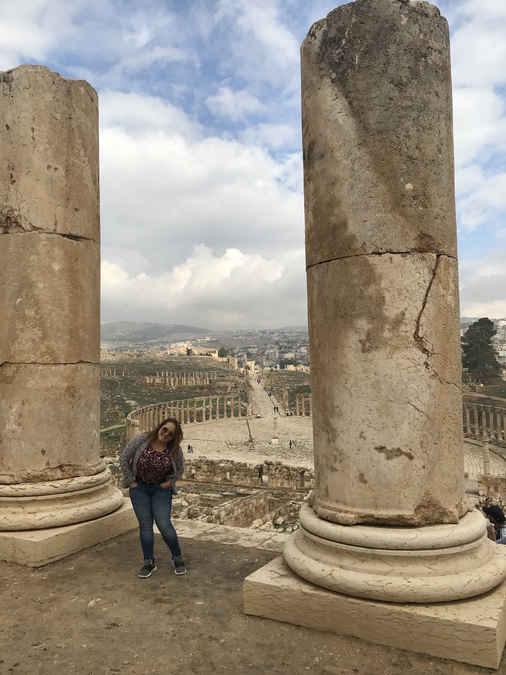 Vue de ruines antiques encadrées par de grandes colonnes avec une personne se tenant à proximité.