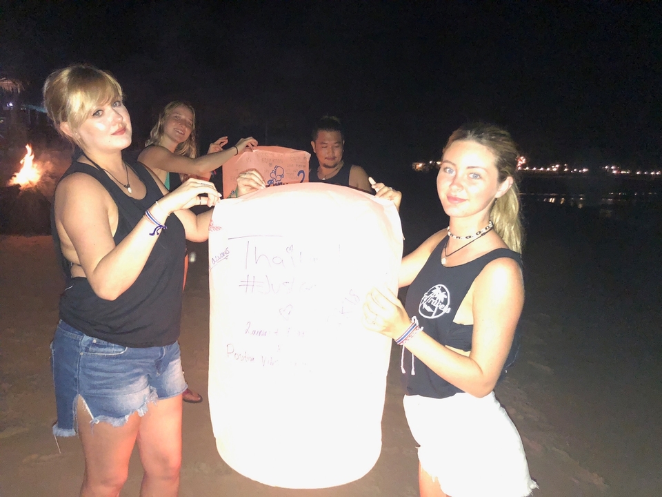 Groupe de personnes tenant une lanterne la nuit sur la plage.