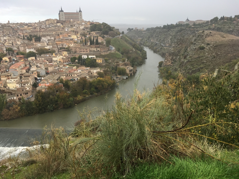 Aerial view of a city along a winding river flanked by hills.