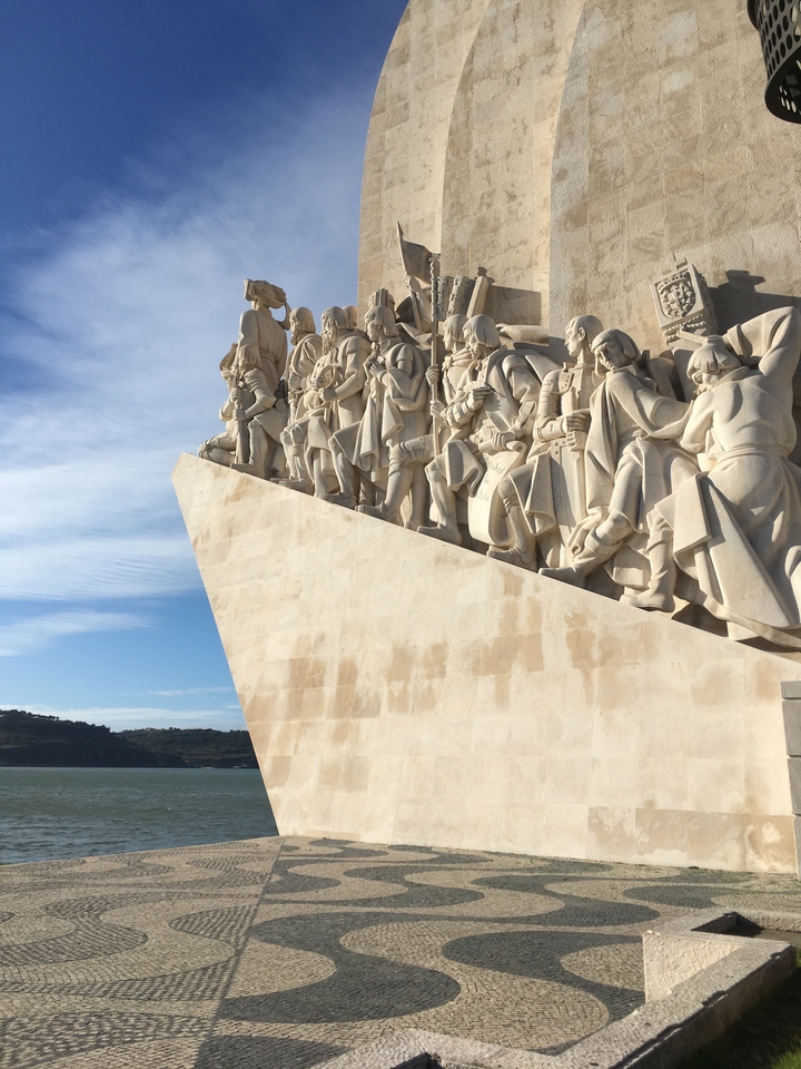 Large carved monument depicting figures reaching up to the sky.