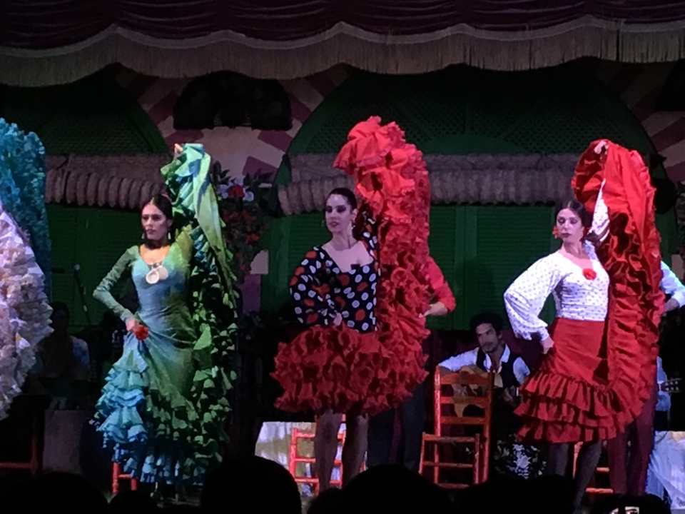 Flamenco dancers in vibrant traditional attire performing on stage.