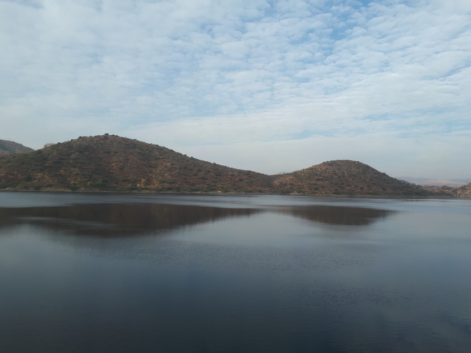 Here's the French translation:
**Étendue d'eau entourée de collines.**
Alternative translation:
**Plan d'eau entouré de collines.**
Both translations are correct, with "étendue d'eau" and "plan d'eau" being common French terms for "body of water."