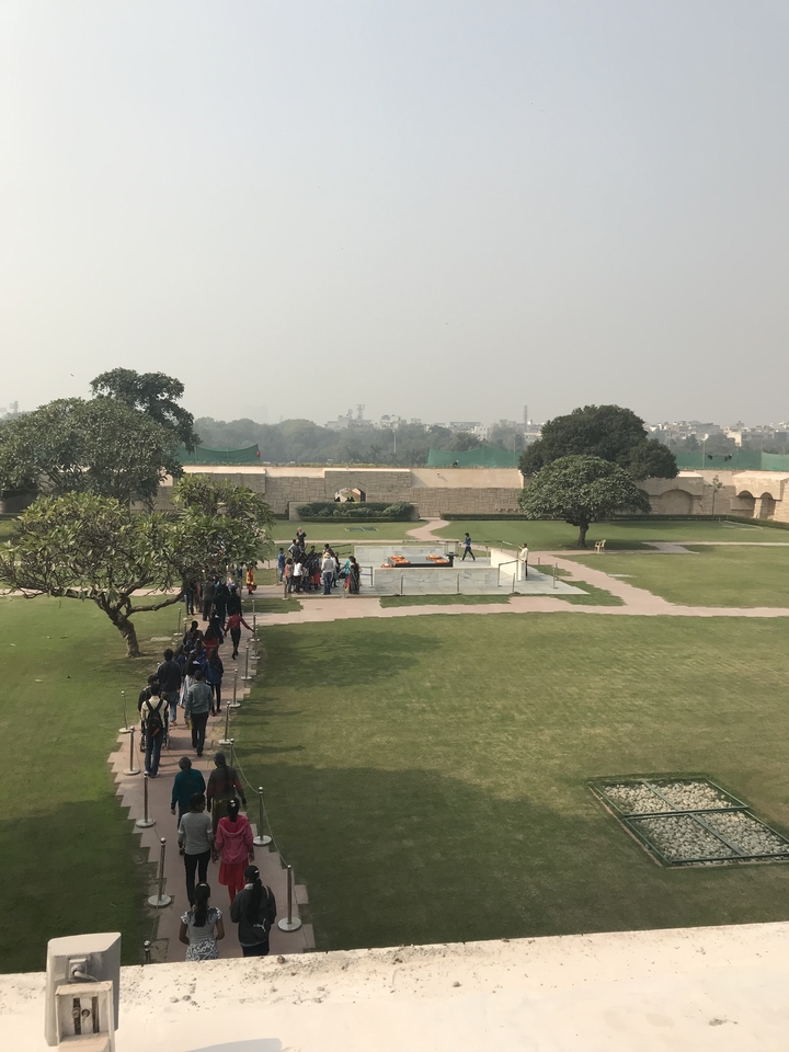 Des gens se promenant dans un jardin à la française avec un horizon urbain au loin.