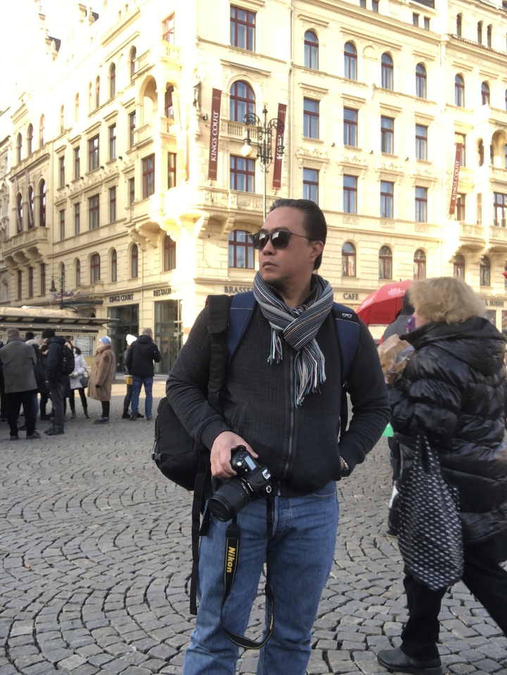 Touriste debout sur une place urbaine animée avec des bâtiments historiques.