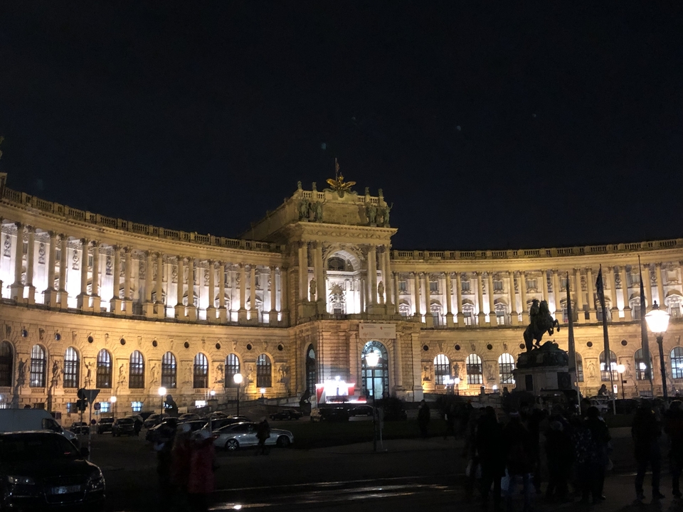 Palais illuminé la nuit avec une statue devant.