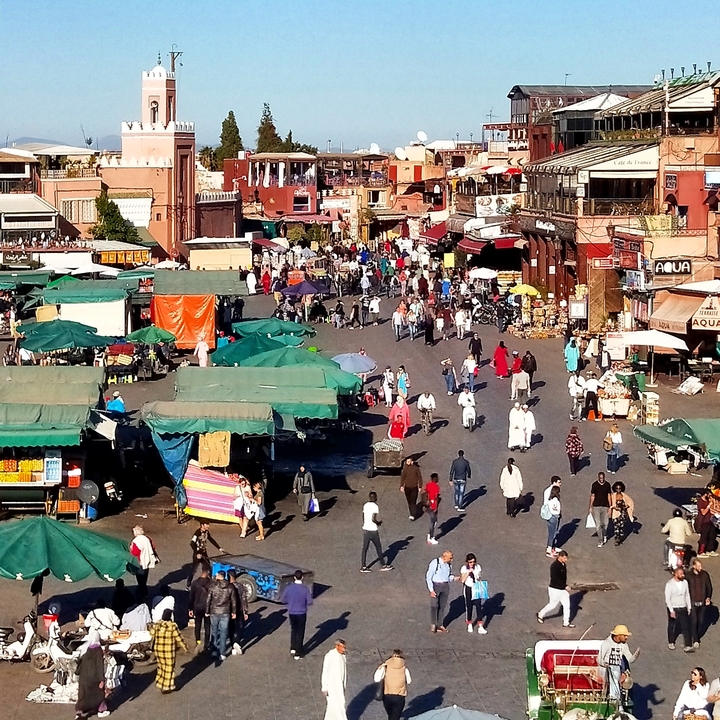 Rue marchande animée avec étals et foule.