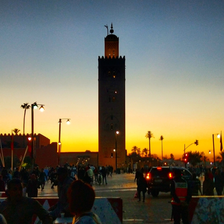 Silhouette d'une tour contre un ciel de coucher de soleil avec des palmiers.