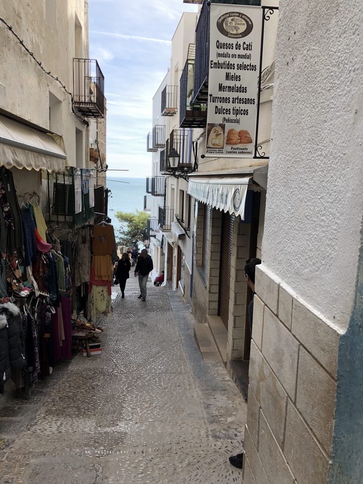 Narrow street with shops leading to the sea.