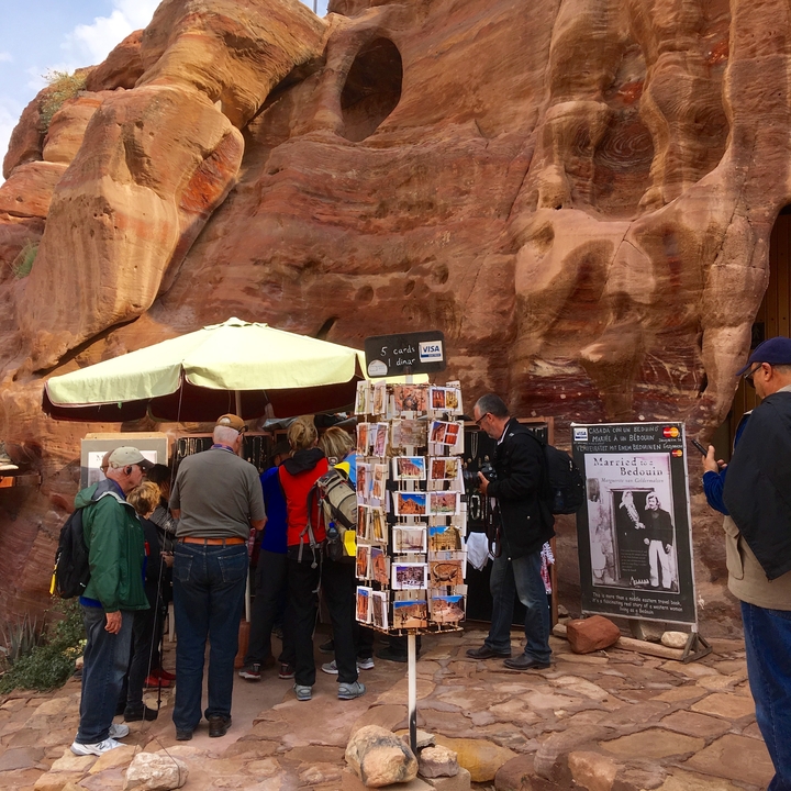 Des gens faisant leurs courses à un étal de marché au pied d'une falaise.