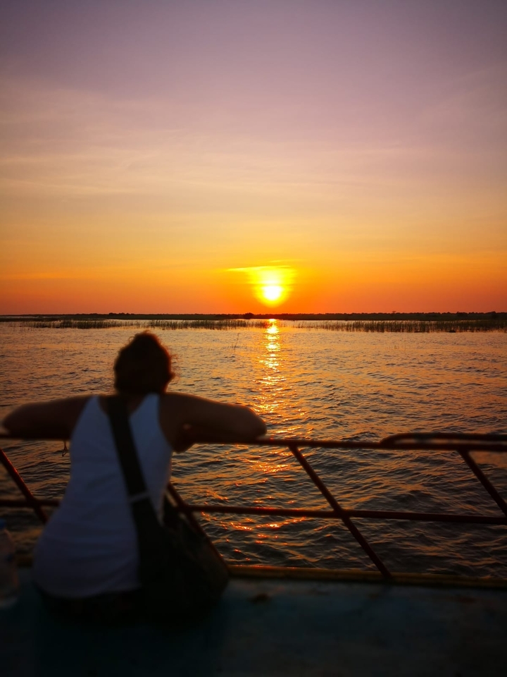 Une personne regardant le coucher de soleil au-dessus d'un plan d'eau.