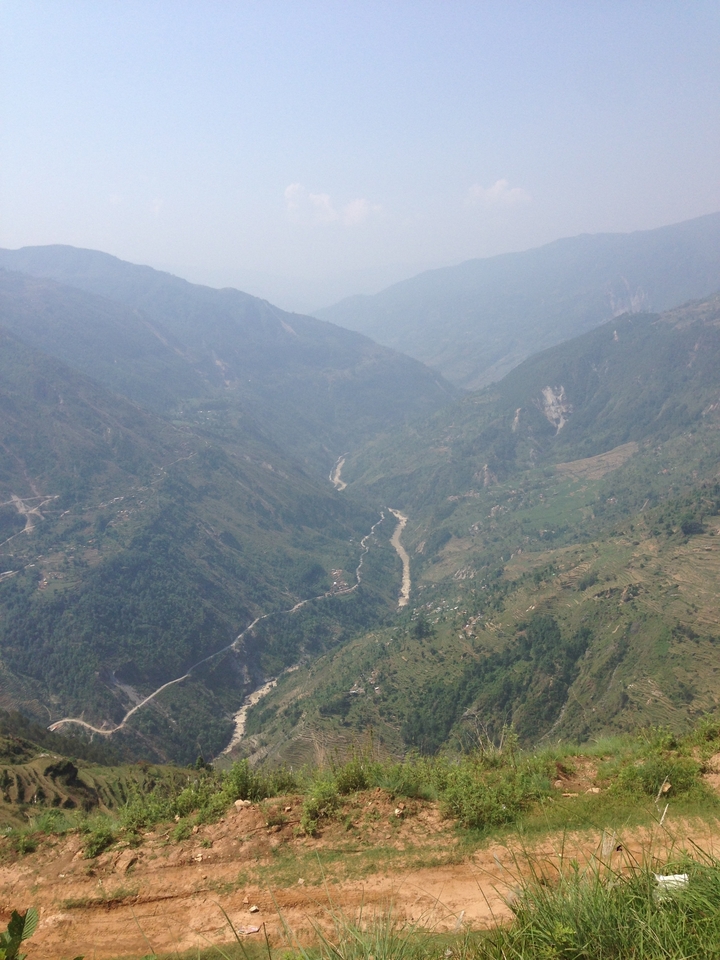 Vue aérienne d'une vallée avec une rivière sinueuse et des collines boisées.