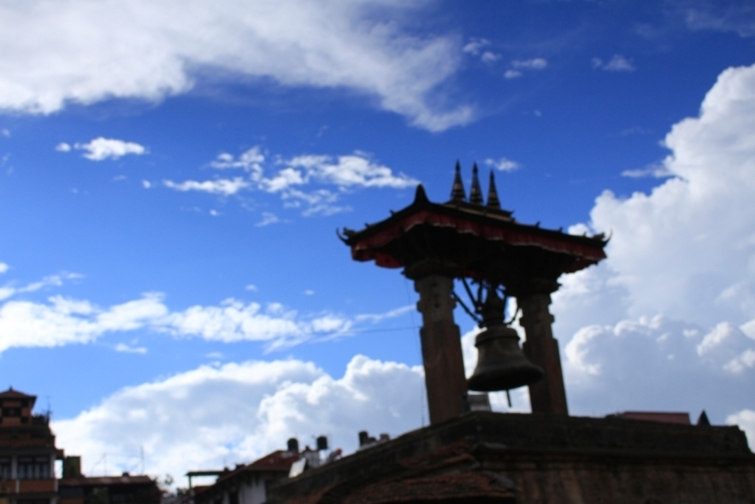 Une silhouette de clocher contre un ciel bleu avec des nuages.