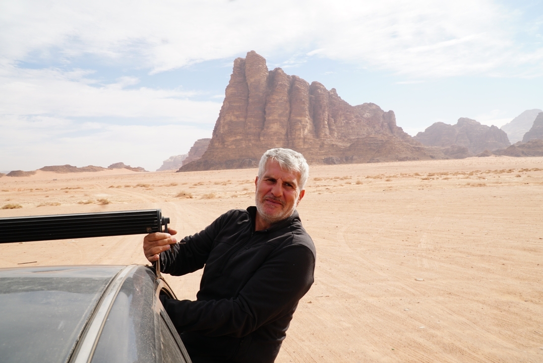 Un homme debout à côté d'un véhicule dans un paysage désertique.