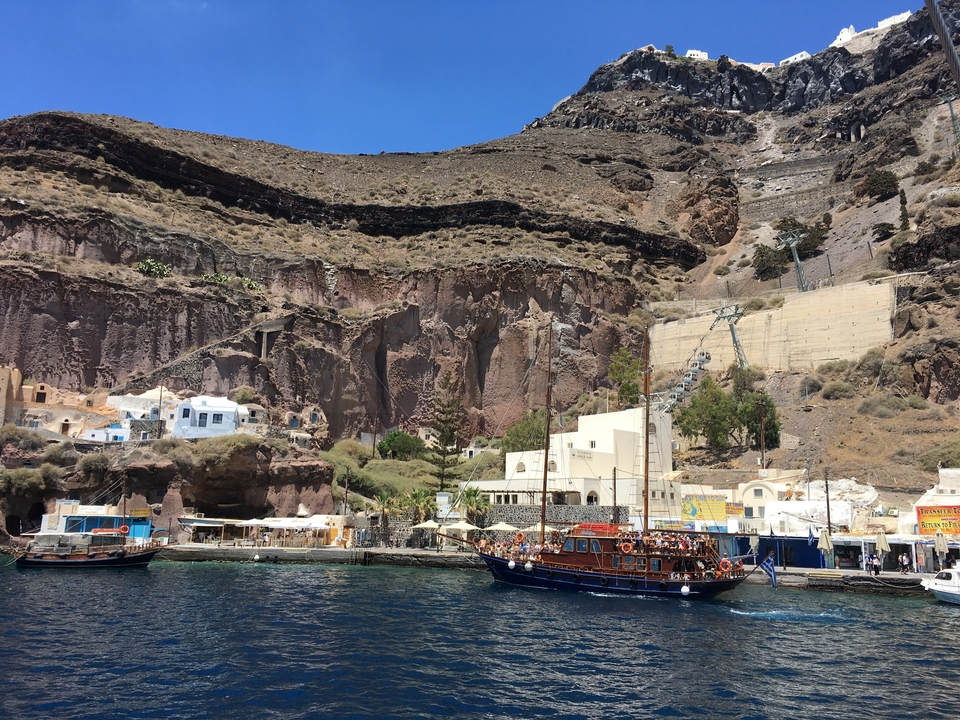Scenic view of a coastal harbor with boats and cliffs.