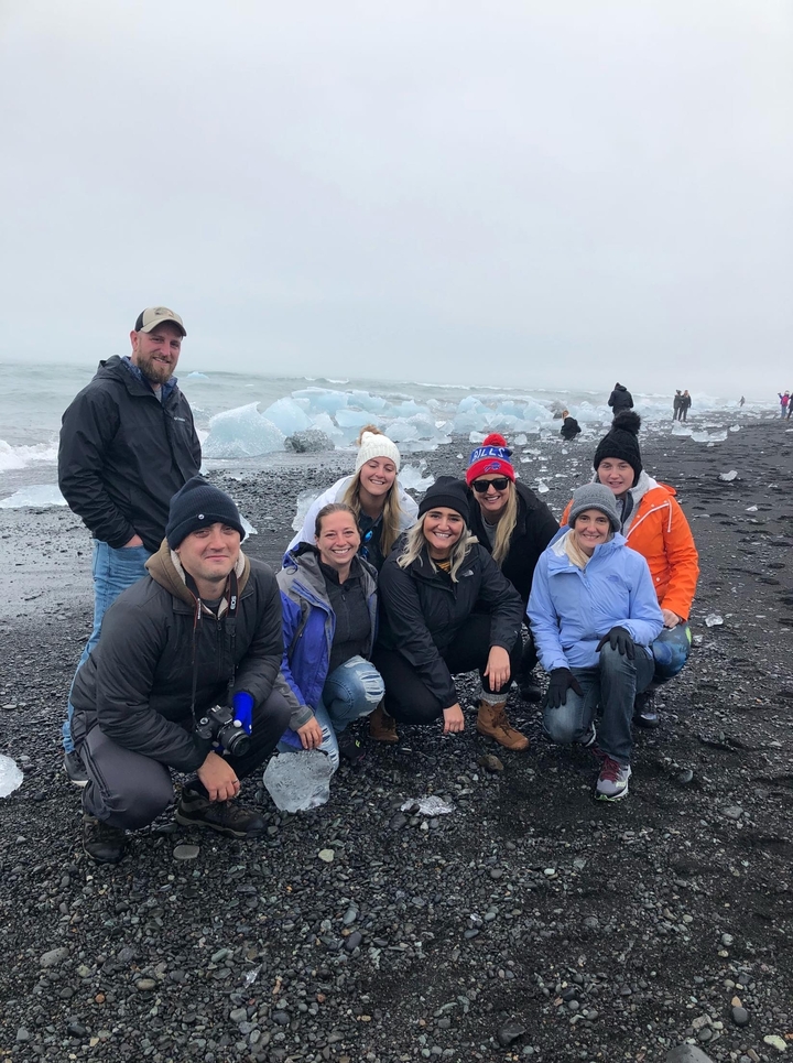 Groupe de personnes sur une plage de sable noir près d'icebergs.