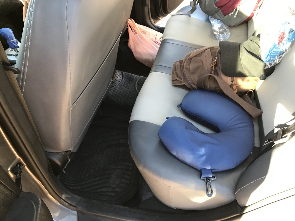 Intérieur d'une voiture avec des sacs et un oreiller cervical.