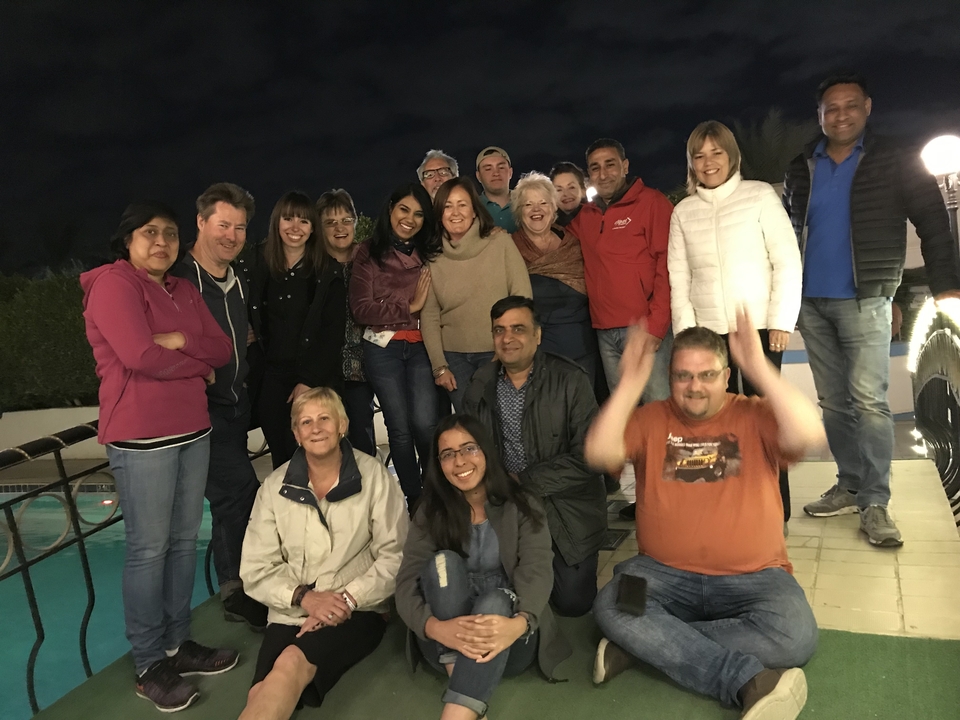 Groupe de personnes posant au bord d'une piscine la nuit.