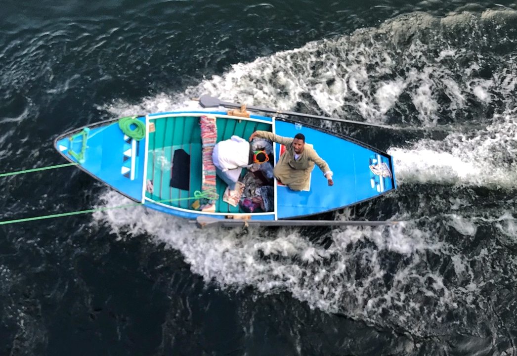Petit bateau en mouvement sur une rivière avec des personnes à bord.