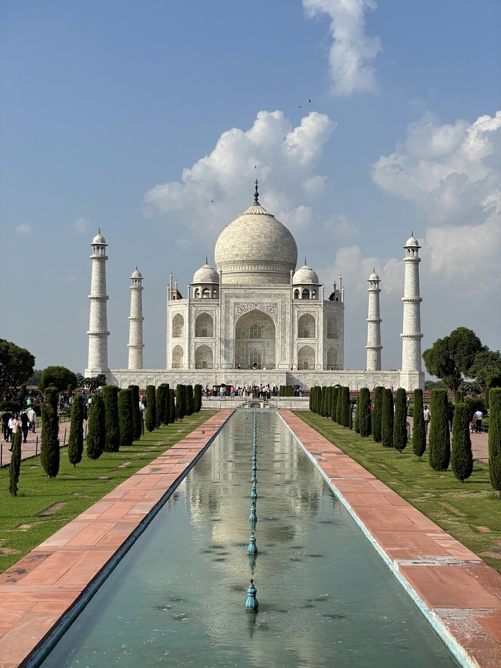 Le Taj Mahal avec son reflet dans l'eau, entouré de verdure.