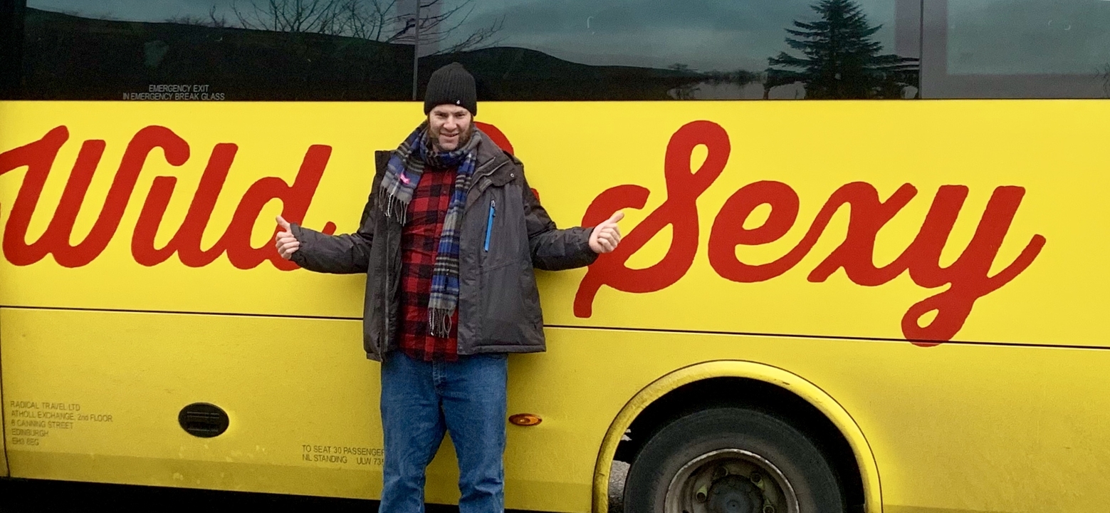 Personne qui pose devant un autobus jaune avec du texte en gras.