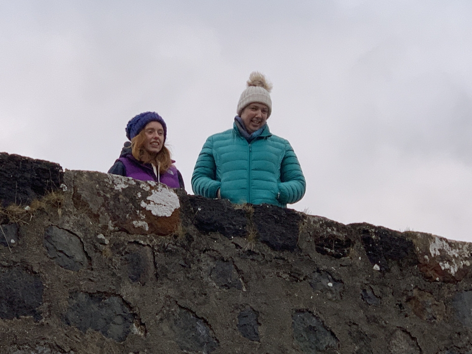 Deux personnes debout sur un mur de pierre regardant vers le bas.