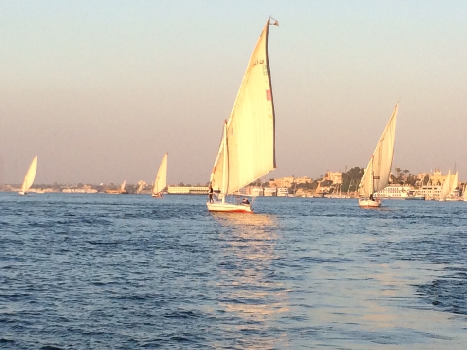 Voiliers sur une rivière au coucher du soleil.
