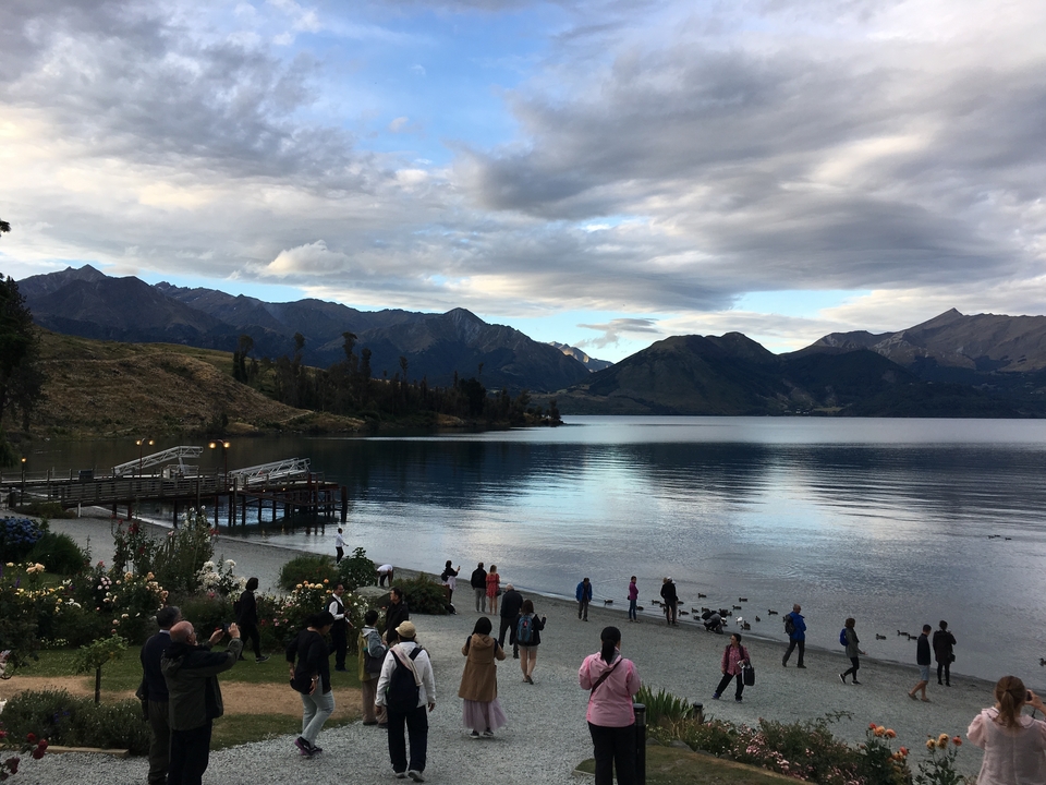 Lac avec des montagnes en arrière-plan, des gens sur la rive.