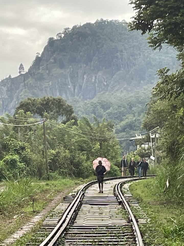 Personne marchant le long des voies ferrées avec un parapluie.