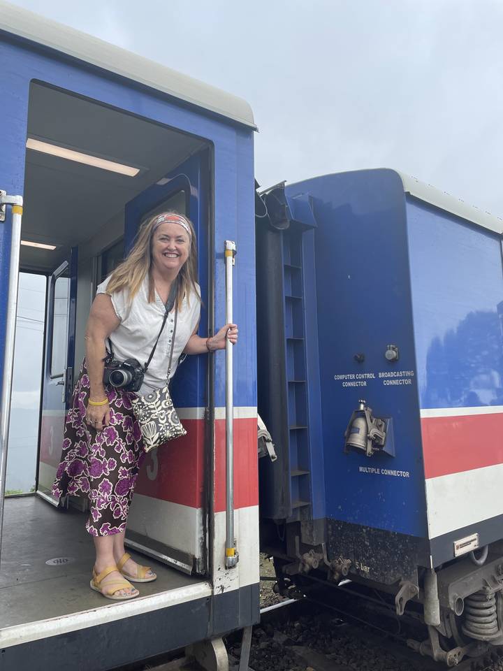 Femme posant à côté d'un wagon de train.