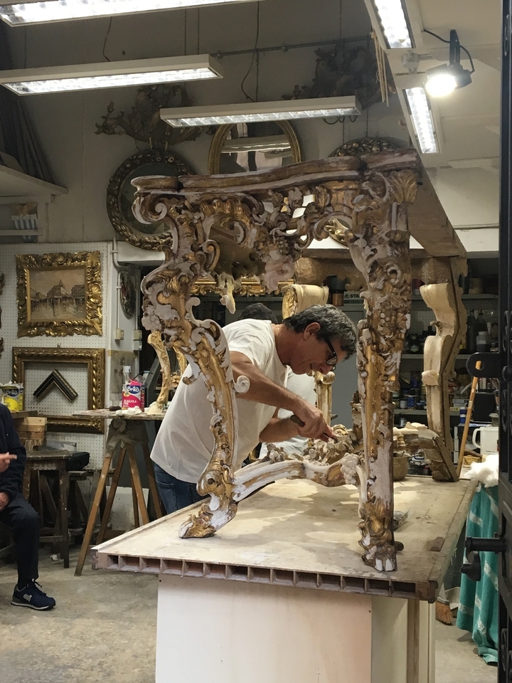 Artisan travaillant sur une table en bois ornée.