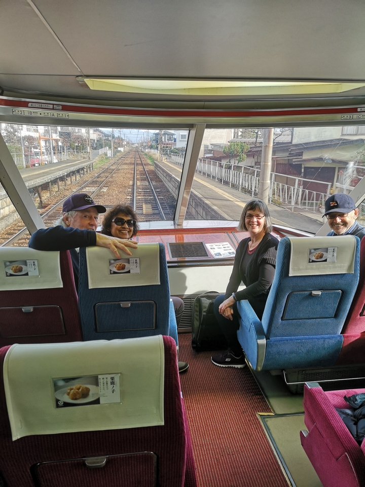 Quatre personnes assises dans un train regardant vers la caméra.