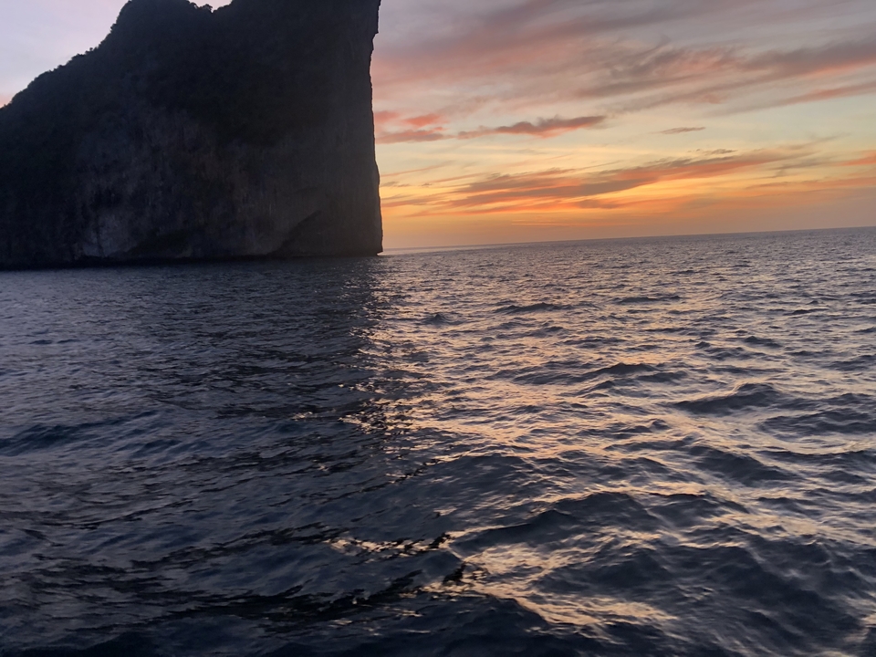 Coucher de soleil sur l'océan avec la silhouette d'un grand rocher.