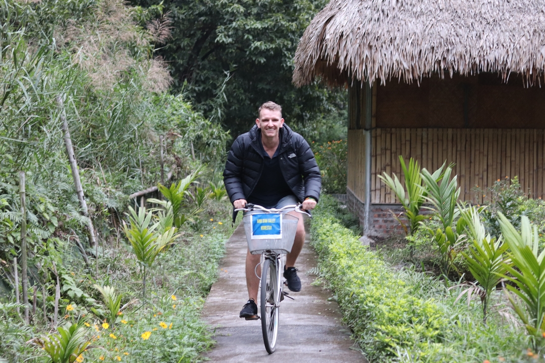 Person cycling on a concrete path with lush greenery around.