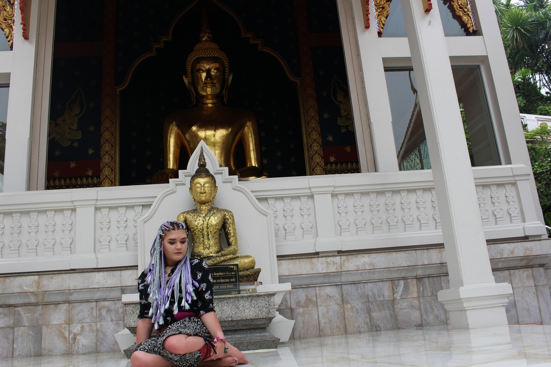 Person sitting in front of a golden Buddha statue.