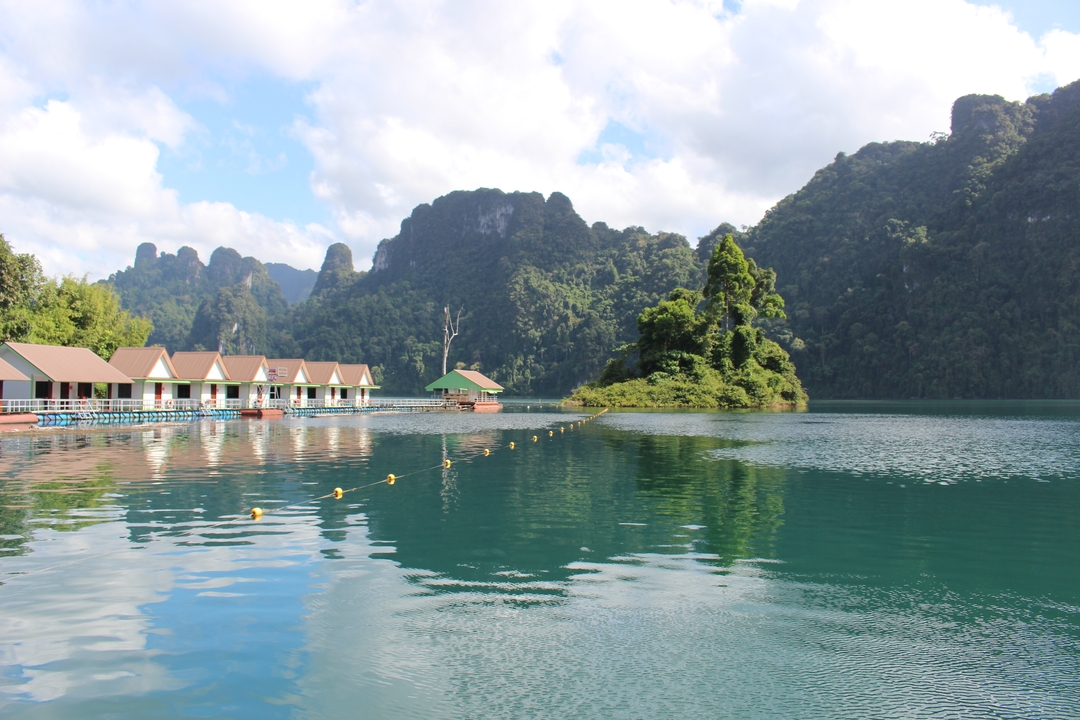 Floating bungalows on a lake surrounded by mountains.