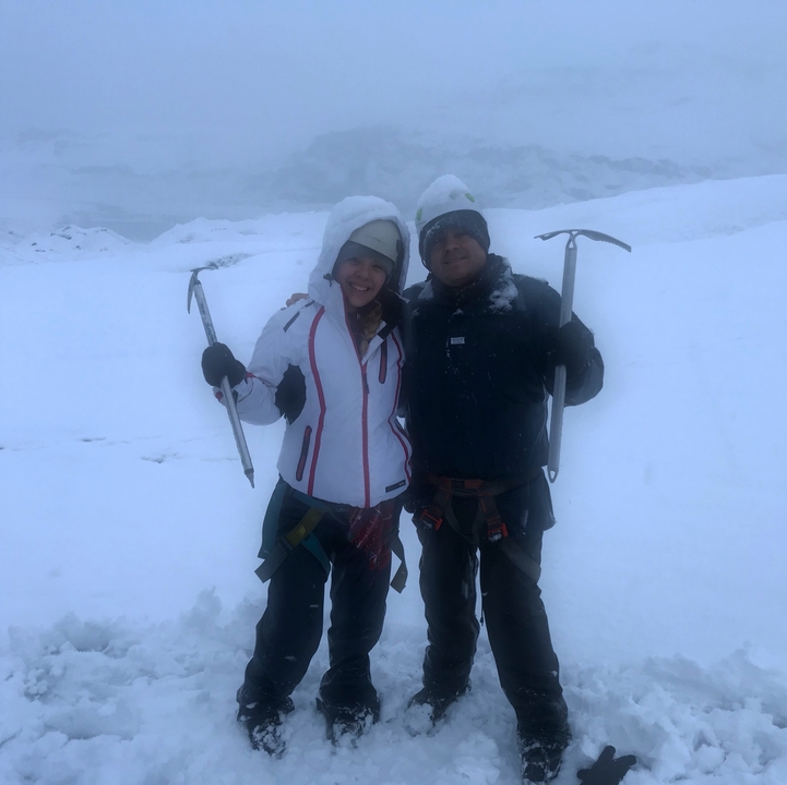 Deux personnes habillées pour l'escalade sur glace dans des conditions enneigées.