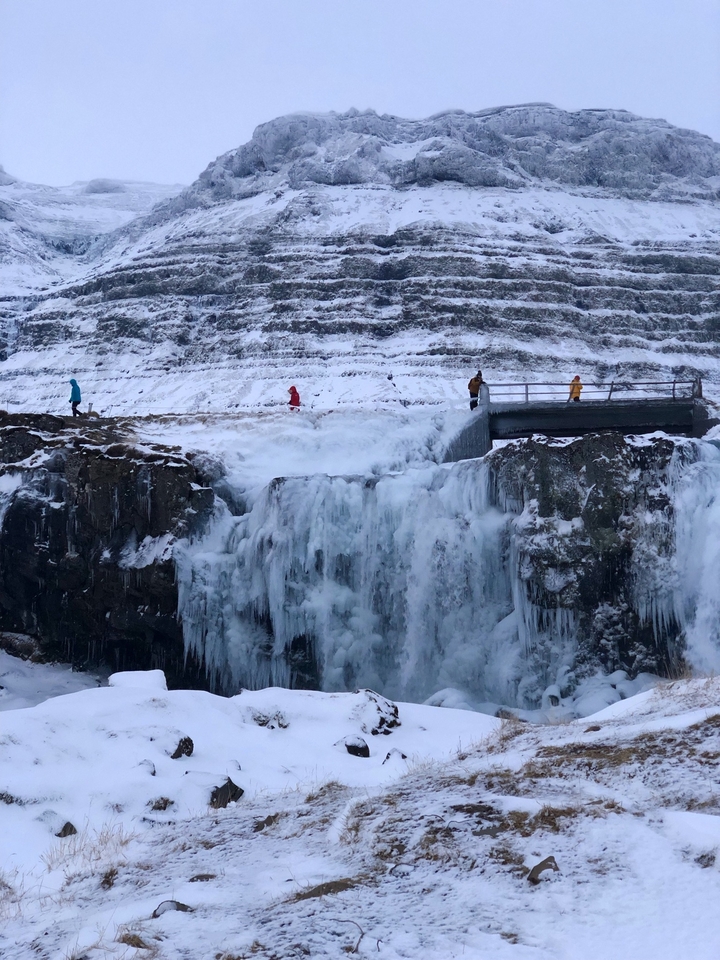 Cascade gelée avec des personnes marchant sur un pont.