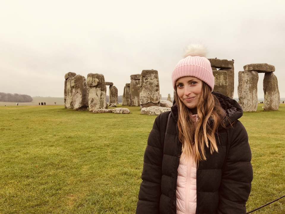 Une personne qui pose avec Stonehenge en arrière-plan.