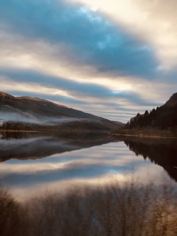 Un lac serein et contemplatif avec des montagnes et des nuages.