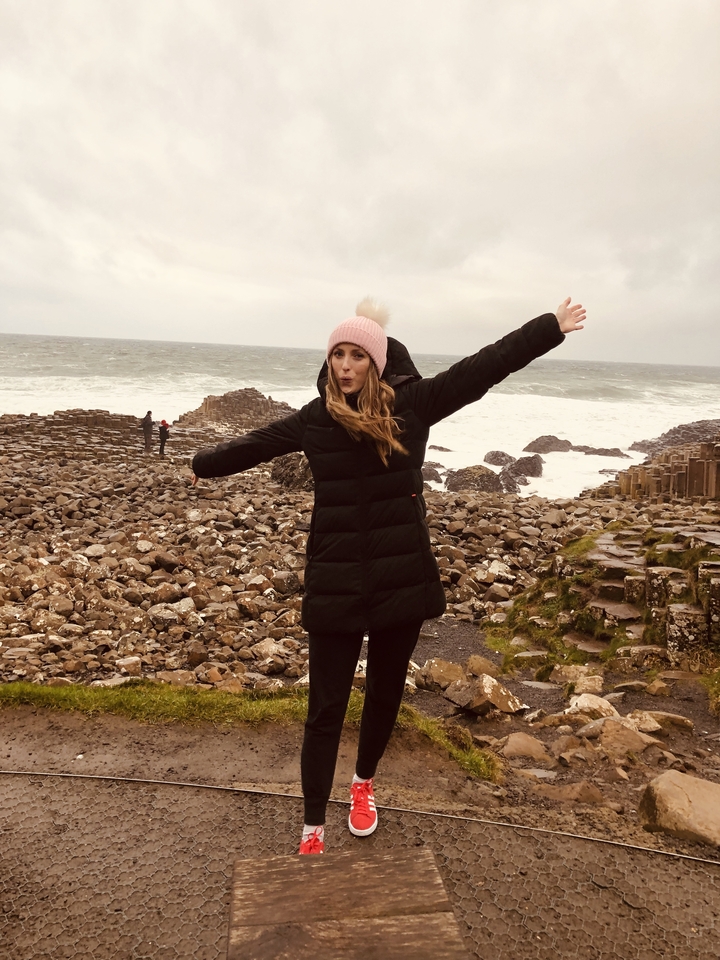 Une personne qui pose avec des formations côtières rocheuses.